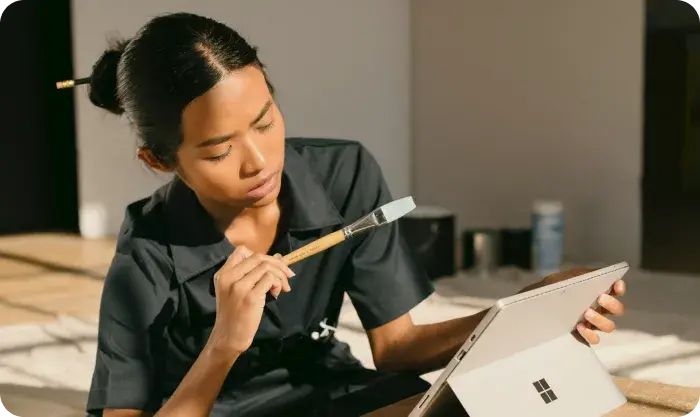 A Woman Sitting On A Box Holding A Paintbrush