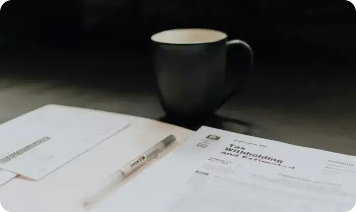 Tax Withholding Forms On Desk With Pen And Mug