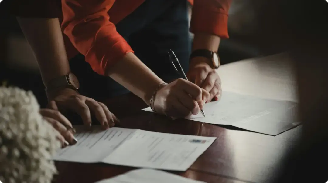 Erson In Orange Long Sleeve Shirt Writing On White Paper