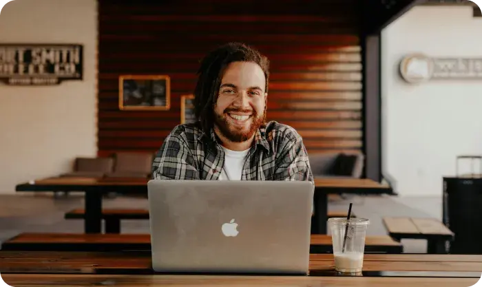 Man Smilling From Hehind Of A Macbook